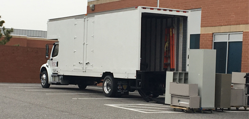 Commercial moving truck loading surplus office furniture and metal cabinets